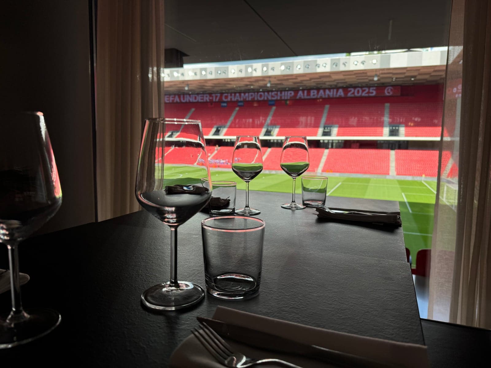Wine glasses on the table with the stadium pitch and a UEFA banner visible through the window