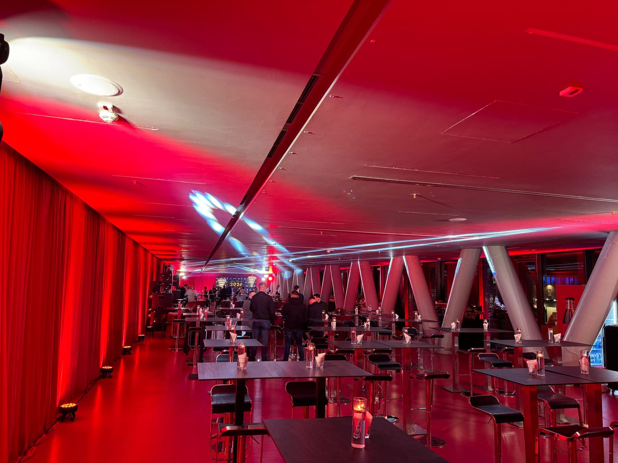 The second-floor VIP suite set up for an event, red light and sculptural columns, before guests arrive