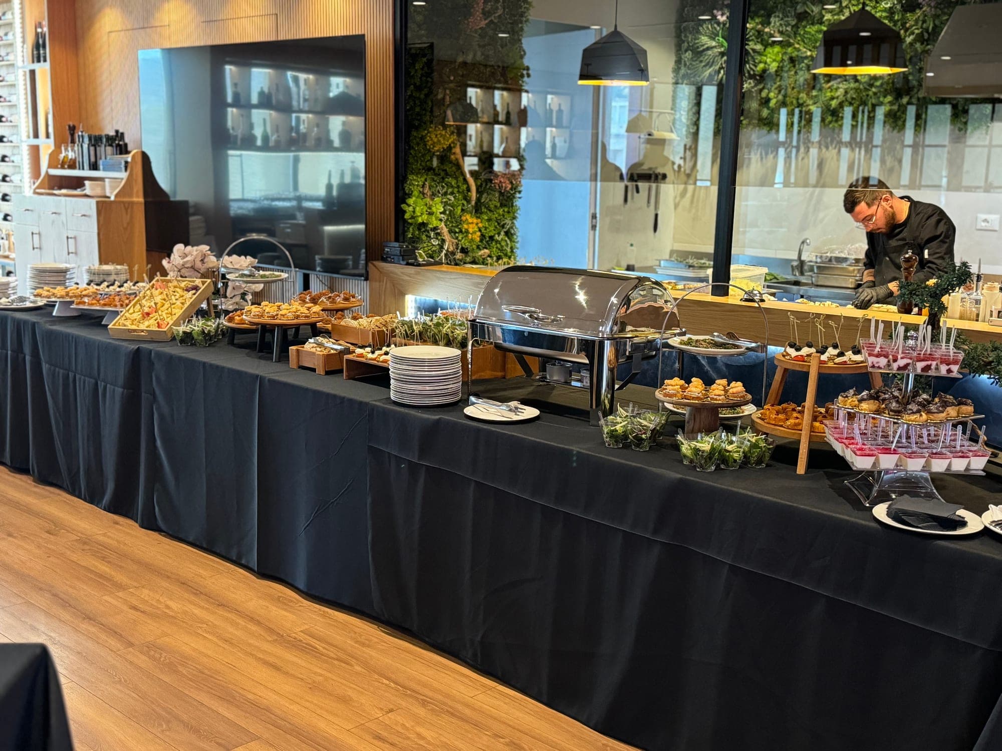 Catering buffet spread along the wood counter and living green wall in the restaurant