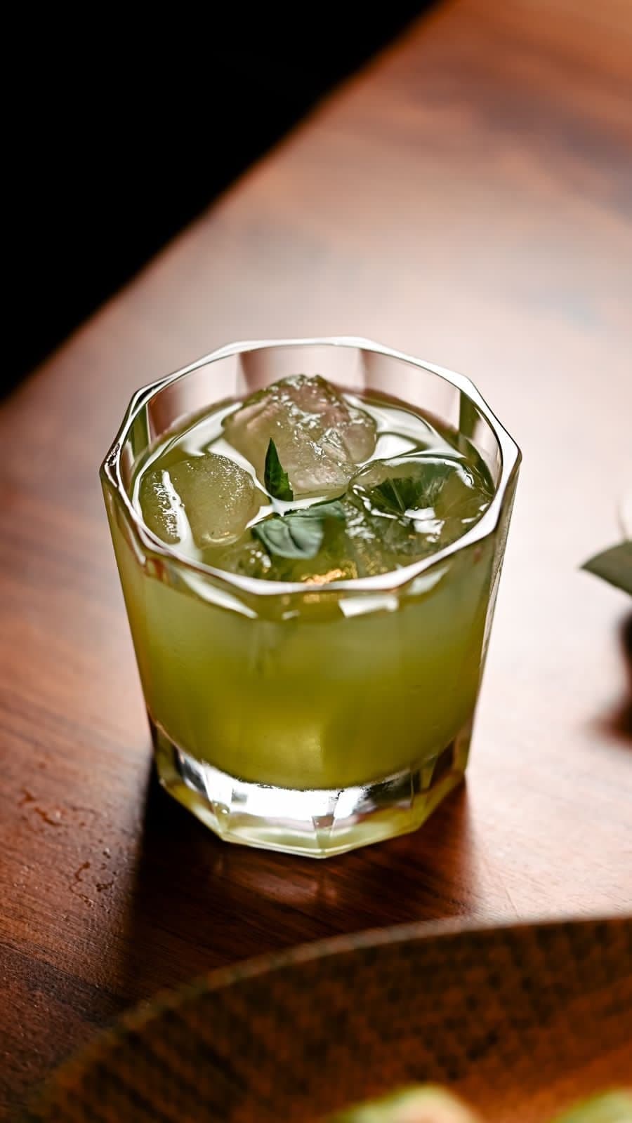 Close-up of a green herbal cocktail garnished and ready to serve