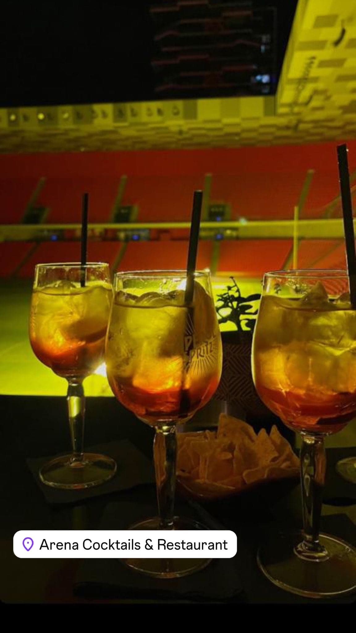 Three cocktails on the bar counter lit by red and green light