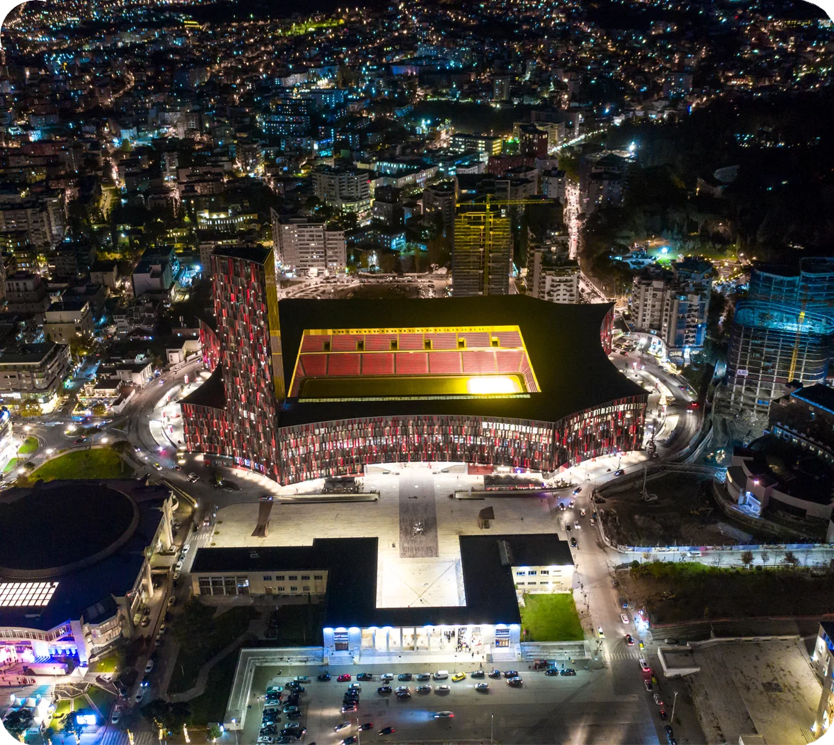 Aerial night view of the floodlit stadium bowl and surrounding Tirana skyline