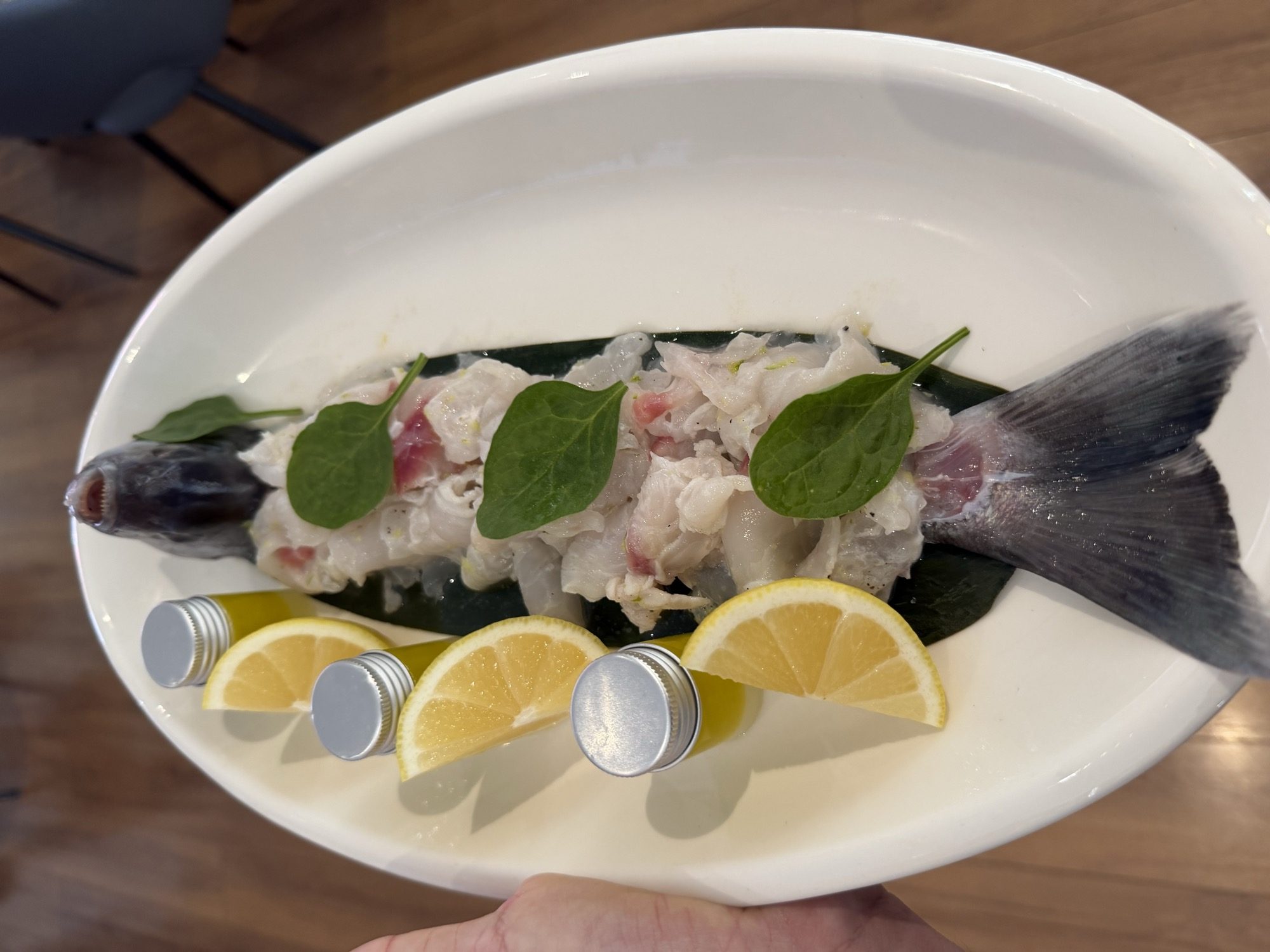 Whole fish crudo plated on a banana leaf with lemon oil