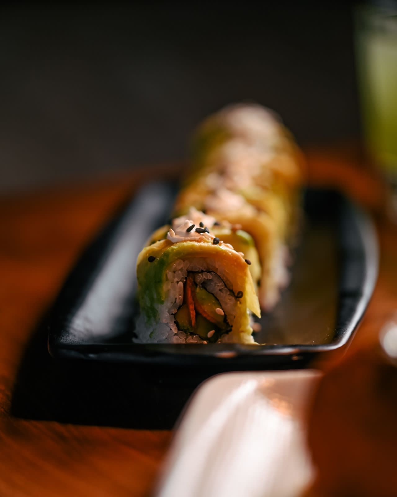 Close-up of a sushi roll plated on a dark tray